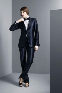 Vrouwelijke smoking gemaakt van glanzende wol en met zijde bewerkte revers en knopen. Mouw is uitlopend gesneden.